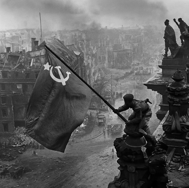 Sovjetsoldaat hijst de vlag van de Sovjet-Unie boven op de Reichstag in Berlijn, symbool van de overwinning in 1945.