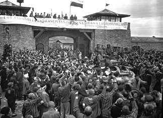 Mauthausen: concentratiekamp, arbeid en bevrijding Bevrijde gevangenen begroeten Amerikaanse soldaten van de 11e Pantserdivisie bij de ingang van concentratiekamp Mauthausen, mei 1945.